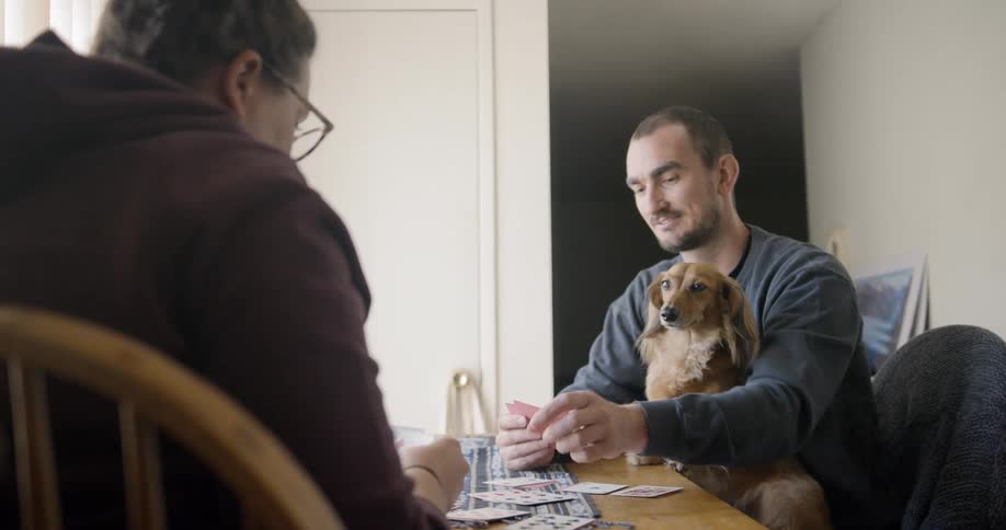 Woman and man sitting at the table play a card game at home