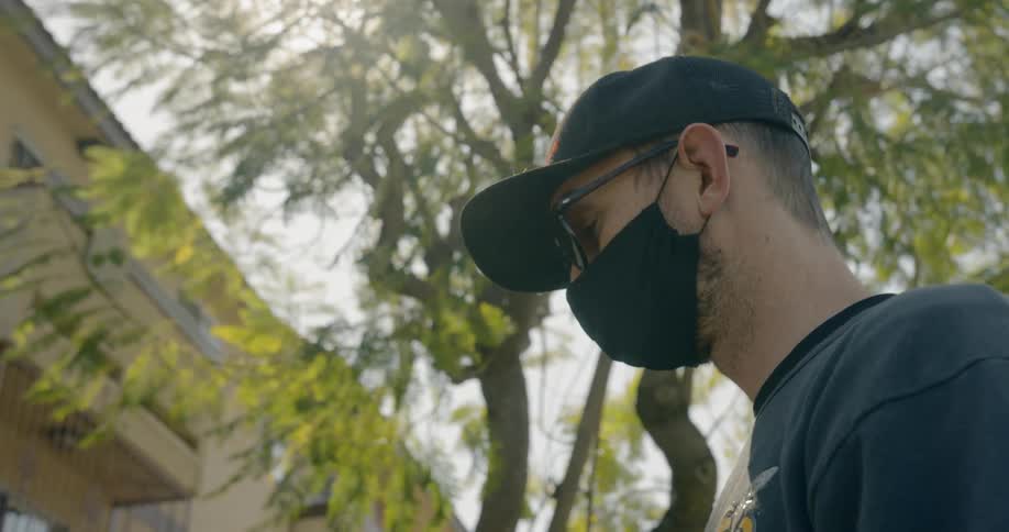 Man wearing a black face mask looks around outside in the city