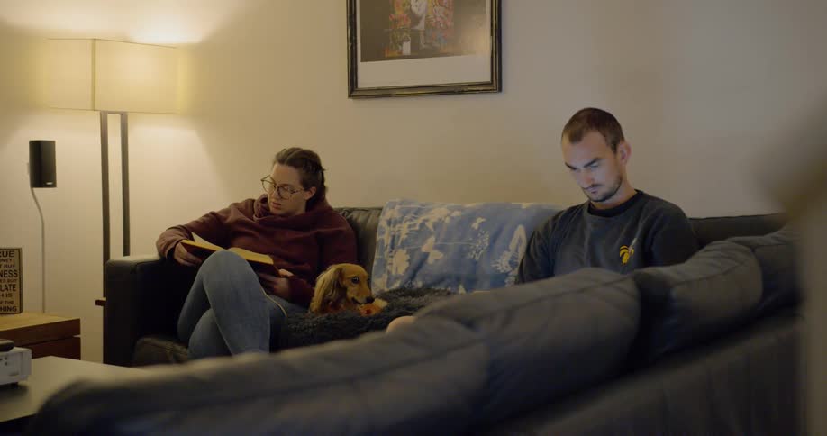 Man and woman sit on the couch in the living room during corona virus lockdown