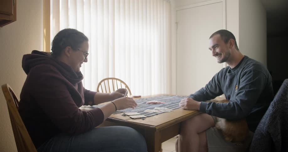 A woman and a man sitting at a table playing cards together