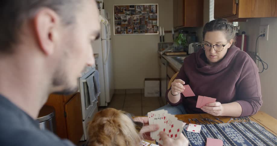 Aman and woman play cards together at a kitchen table