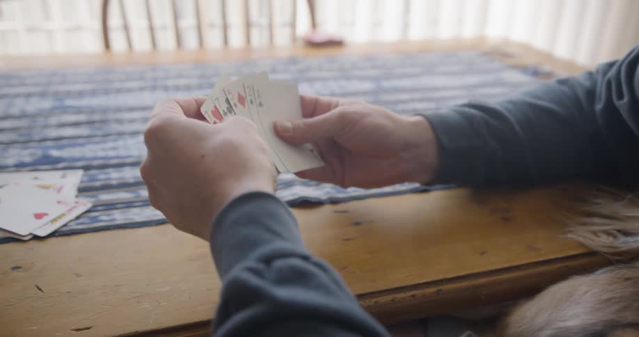 Man and woman sitting at the table play a card game at home