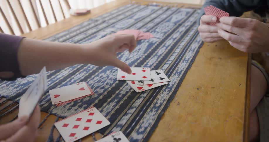 Couple sitting at table plays cards in the kitchen