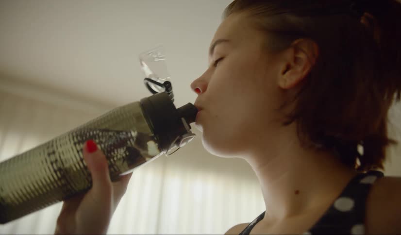 The woman drinks her water from a bottle