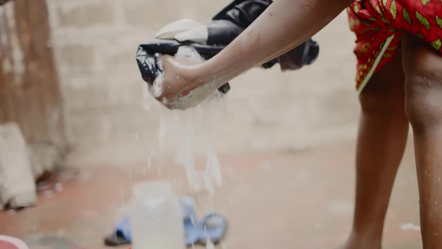 A person is washing their clothes in a bucket