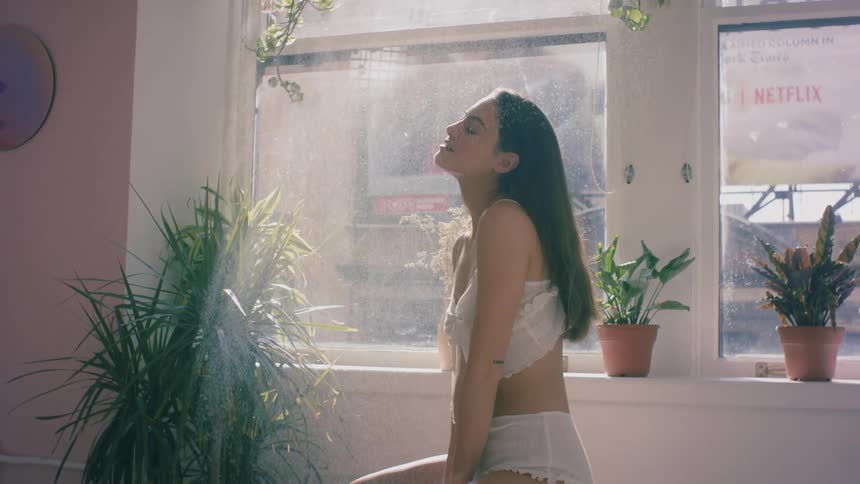 A woman sits inside as water splashes down on her