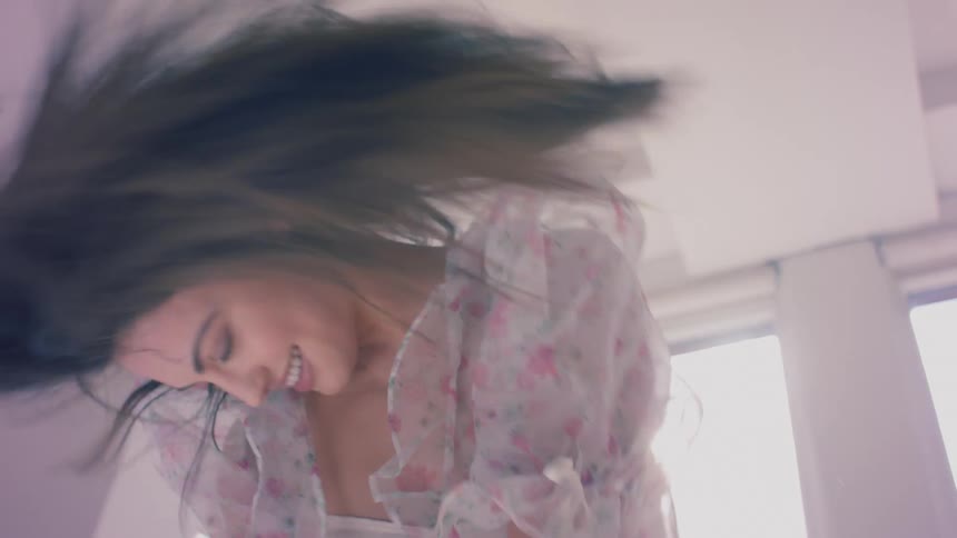 A woman dancing and smiling shaking her hair and head around