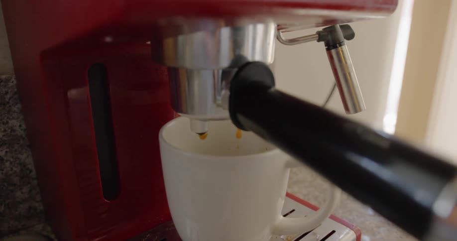 Espresso machine in kitchen countertop pouring hot coffee on a cup