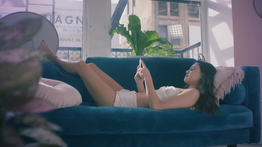 A woman laying on the couch looking at a smart phone