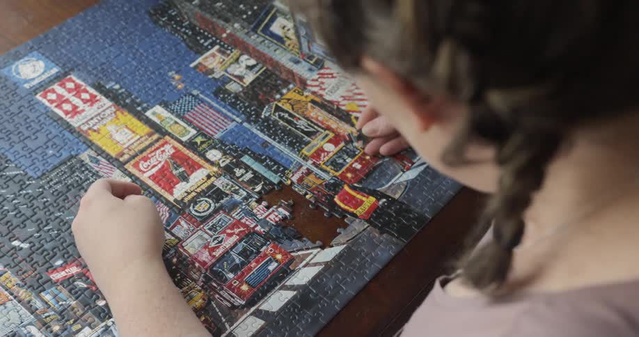 A woman holds and places some of the last pieces of a large jigsaw puzzle