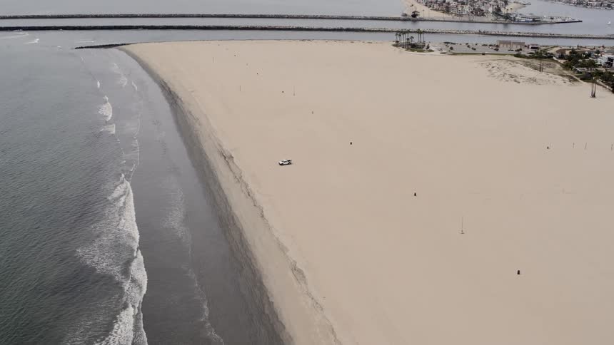 Aerial of waves crashing on the shoreline on a closed beach