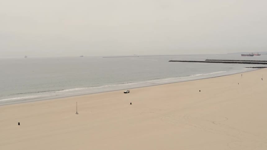 Vehicle driving in the sand of empty beach at day
