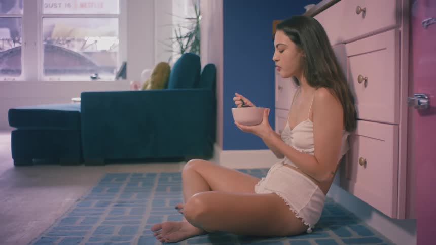 A woman sitting on the floor eating a bowl of cereal