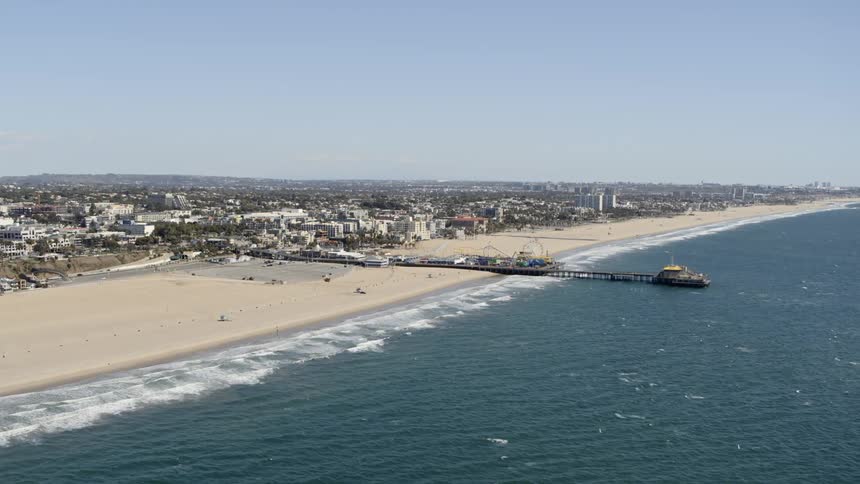 Aerial view of ocean waves crashing against sandy beach during daylight