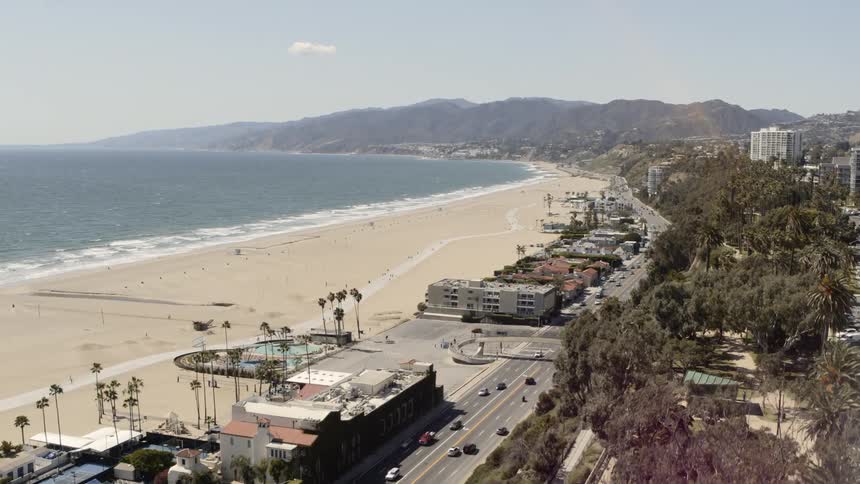 Vehicles travel along a beachside highway and town