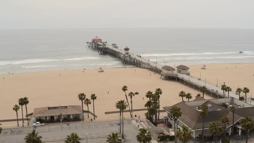 People running and walking along the beach by a pier