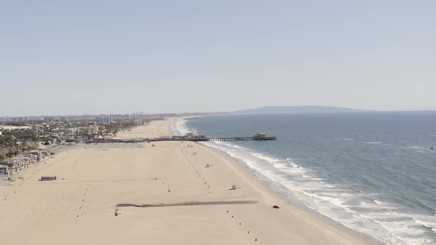 Waves roll into a beach near a city