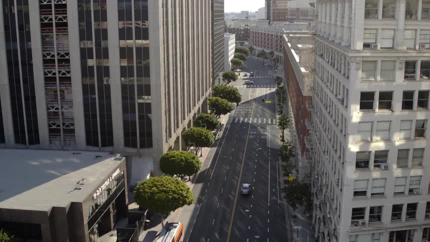 A bus and cars drives down a nearly empty city street