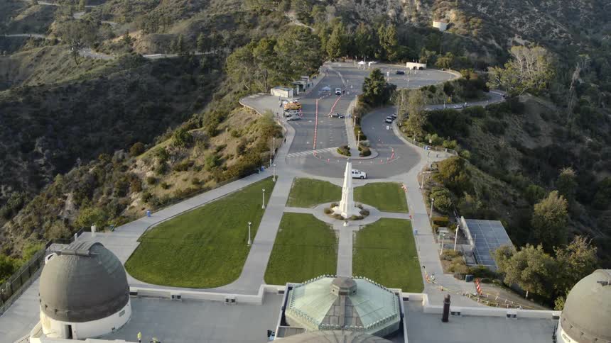 A scattering of cars and a couple of people visiting the closed griffith observatory on a sunny day