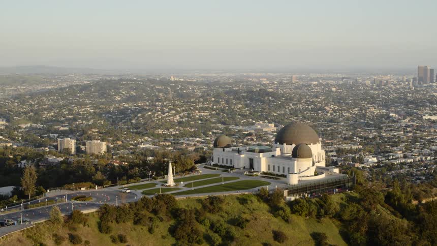 A religious building sits on a hillside with cityscape in the background