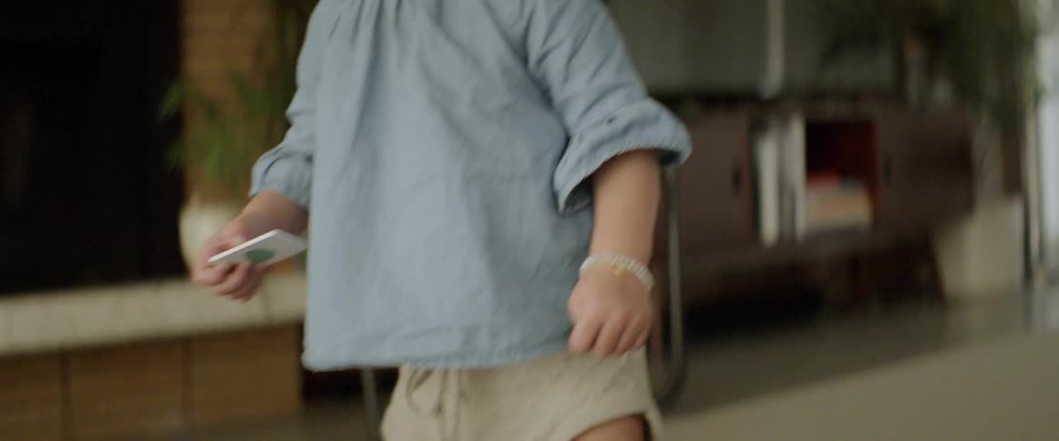 A toddler bends down and picks up a toy tile from the floor