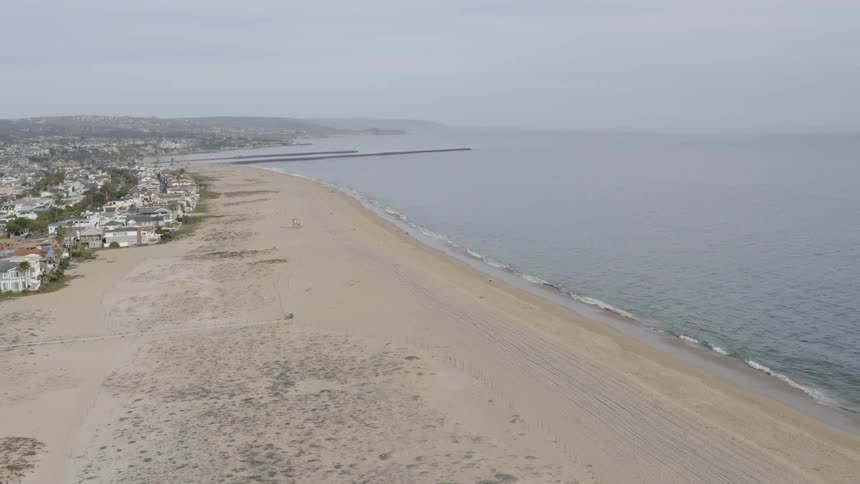 Aerial view of the sand beach next to the sea on a cloudy day
