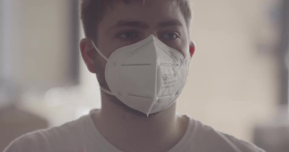 A teenager places a mask over his face