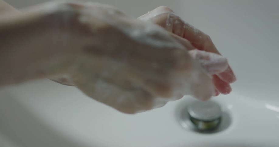 Woman washes her hands with soap in the bathroom