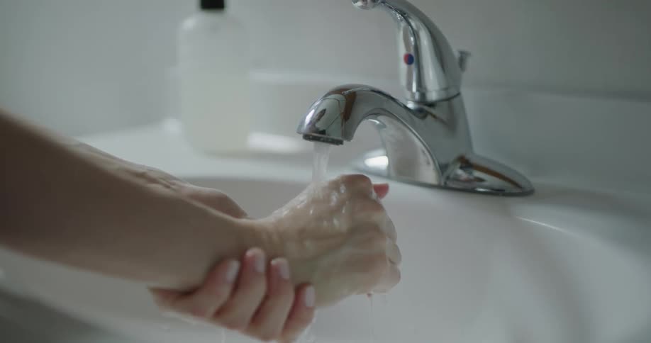 Woman washes her hands with soap in the bathroom