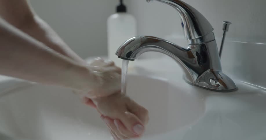 Woman washes her hands with soap in the bathroom