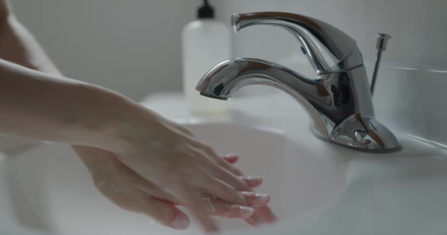 A woman washes her hands at a sink