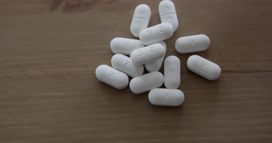 A woman dumps a container of pills on to a table