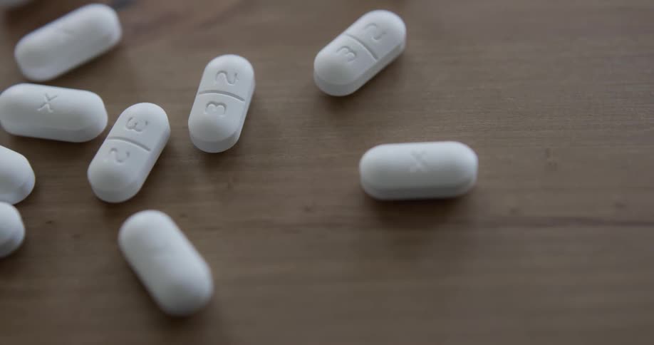Pills being poured onto a table from a paper pouch