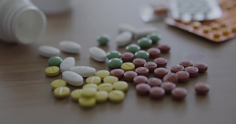 Multicolored pills lay on a table with open bottles a pill packs