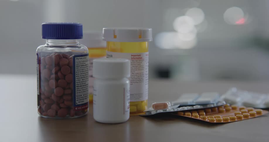 Bottles and blisters of pills and capsules on a table