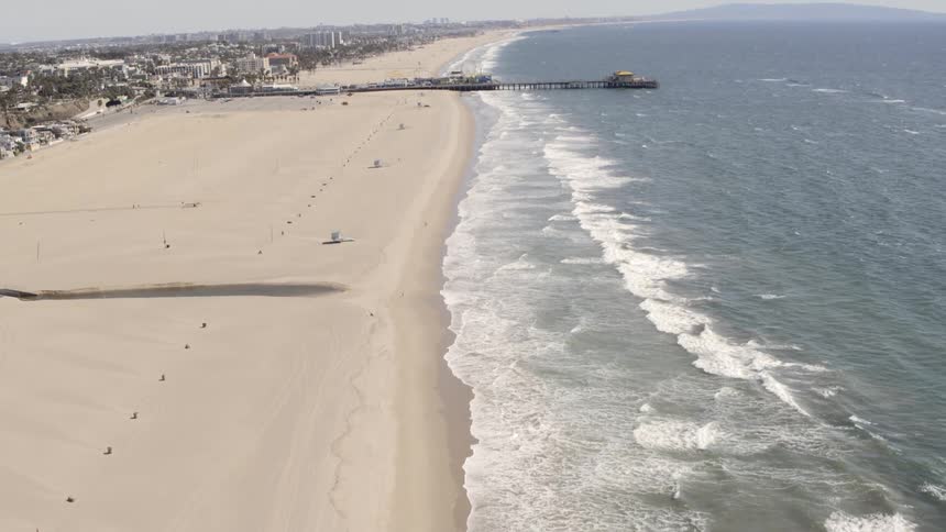 Aerial view of the ocean waves crashing against the shore on a sunny day
