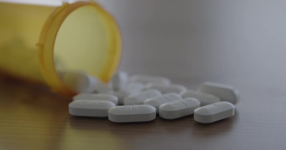Pills spilling out of a bottle on to a table