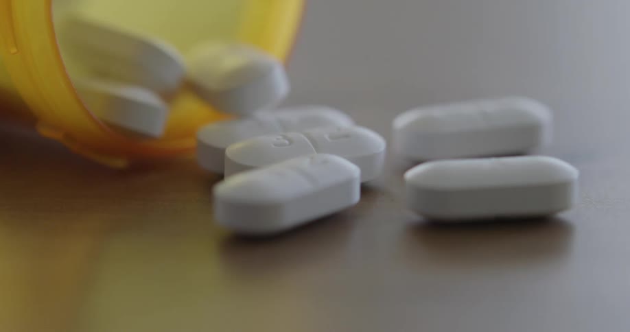 Pills from a translucent bottle on a wooden table