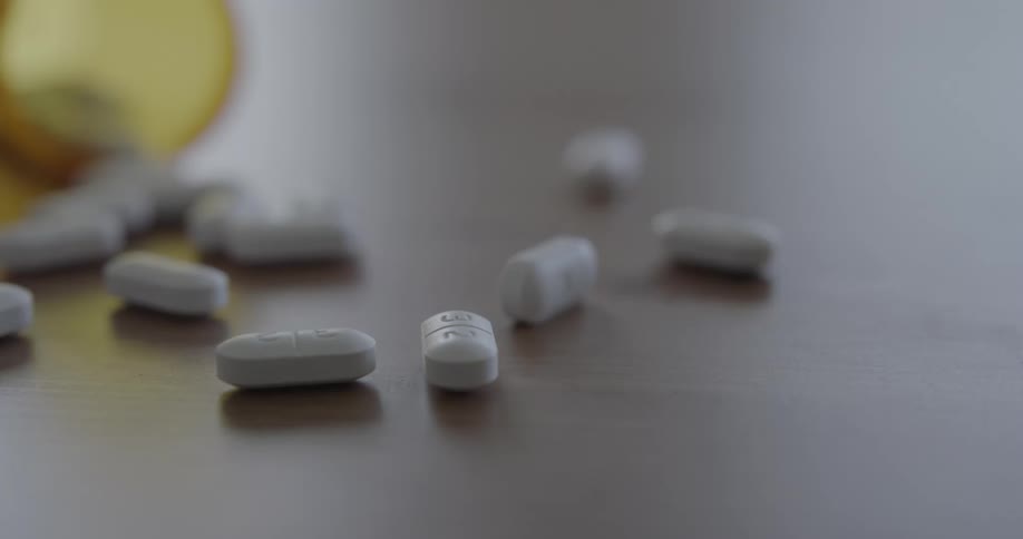 Pills from a translucent bottle on a wooden table