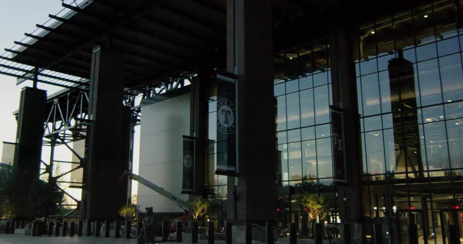 Lights glow inside and reflect on the glass of the empty texas rangers baseball park entrance