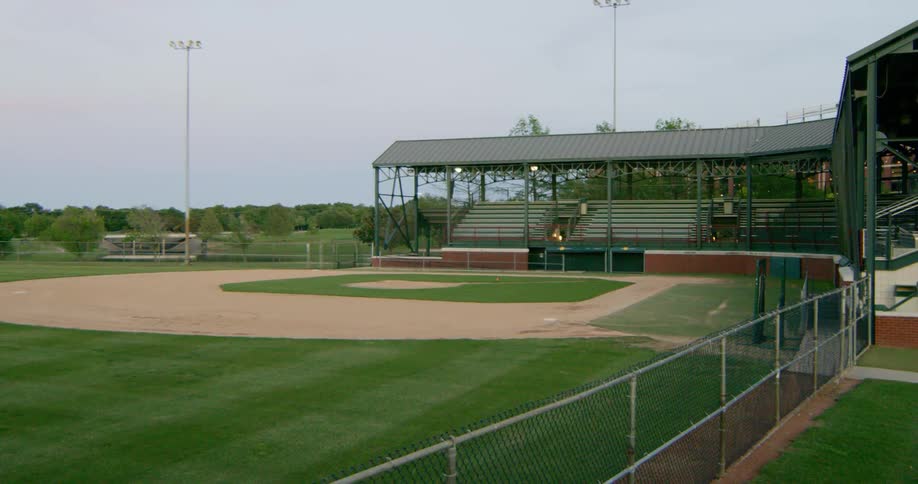 Lights glow above the stands at an empty baseball field