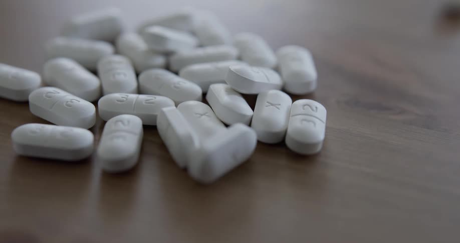 A hands pours pills onto a wooden table