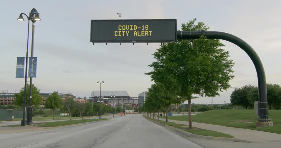 Led sign regarding covid19 stands near intersection with buildings in distance