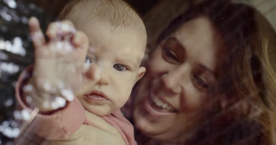 Mother and daughter smiling behind window glass