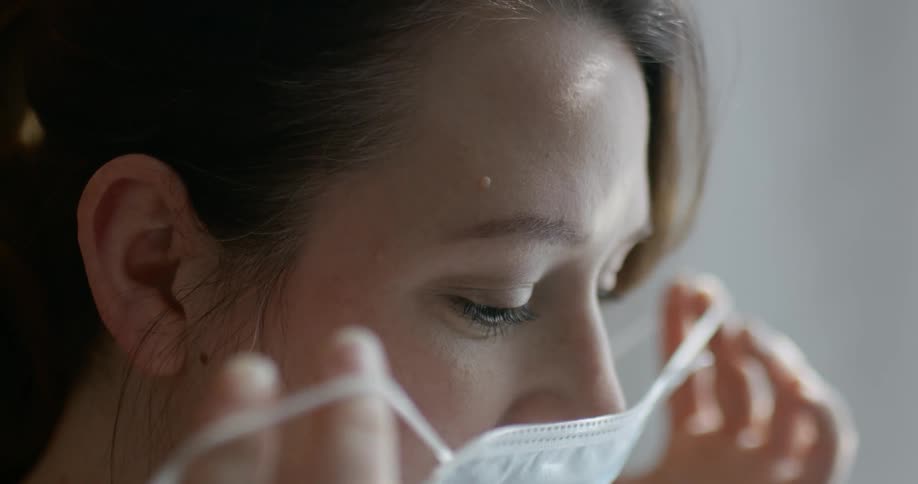 A young woman puts a mask on her face