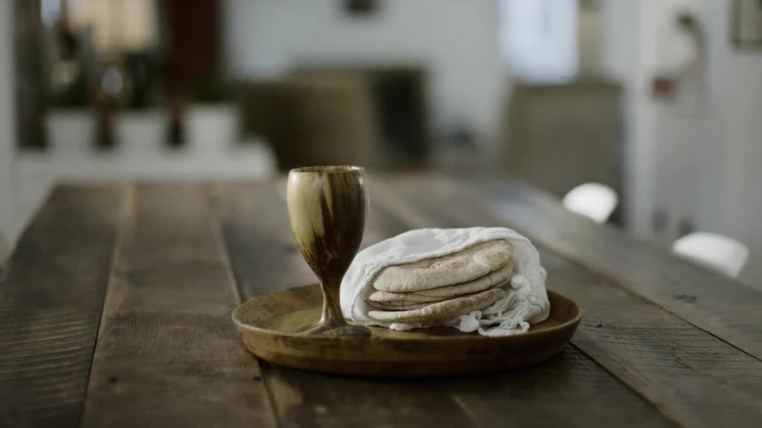 A table with a serving tray a cup and flatbread wrapped in a towel