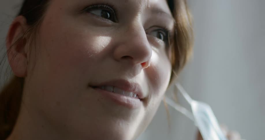 A woman removes her mask