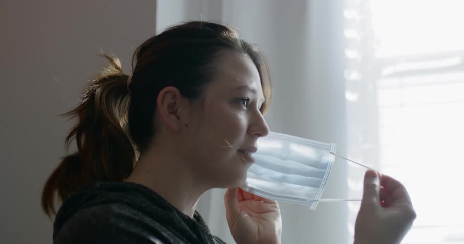 A woman takes off a medical mask