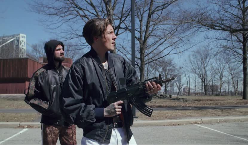 A man shoots an automatic rifle in a parking lot
