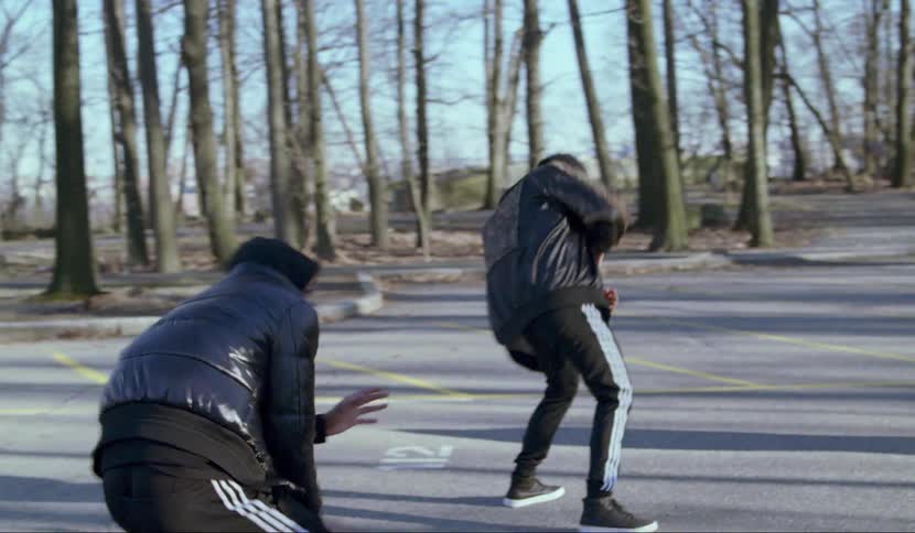 People dance around a black object in a parking lot